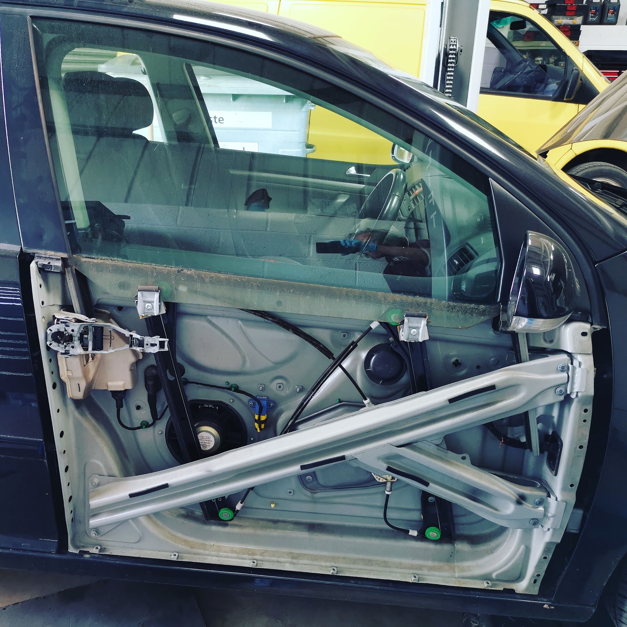 A car door with the door card removed, showing the window regulator and frame